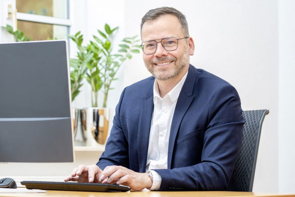 Senior Finanzierungsberater Tobias Barth sitzt am Schreibtisch im Würzburger Büro von Henneberger Finanzierung