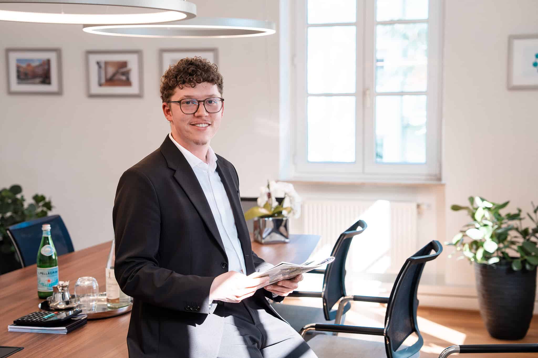 Mitarbeiterfoto: Lenny im Besprechungsraum mit Unterlagen in der Hand
